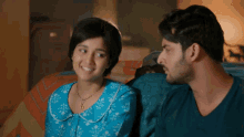 a man and a woman are sitting on a couch and smiling at each other