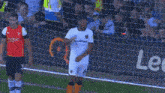 a soccer player wearing a white jersey with the number 1 on it is kicking the ball