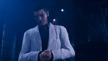 a man in a white jacket and sunglasses is standing in the dark .