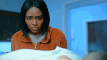a woman in an orange jacket is looking at a blanket