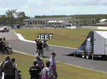a group of people watching a motorcycle race with jeet written on the bottom right