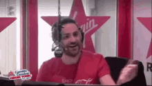 a man wearing headphones and a red shirt is talking into a microphone .