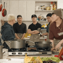 a group of young men are cooking in a kitchen and one of them is wearing a shirt that says okay