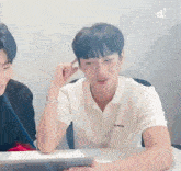 a man in a white polo shirt is sitting at a table with another man .