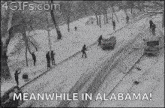 a black and white photo of a snowy street with people standing on the sidewalk .