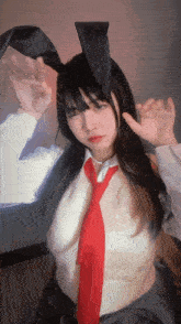 a girl wearing bunny ears and a red tie is making a funny face