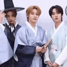 a group of young men are standing next to each other wearing traditional clothes and hats .