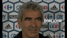 a man is standing in front of a wall with adidas logos on it