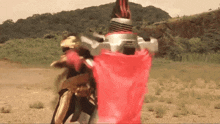 a person in a red cape is standing in a field holding a sword