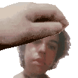 a hand is holding a piece of paper over a man 's face .
