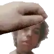 a hand is holding a piece of paper over a man 's face .