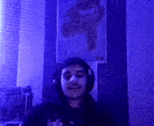 a man wearing headphones is standing in front of a blue curtain .