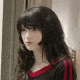 a woman with long black hair and bangs is standing in a doorway .