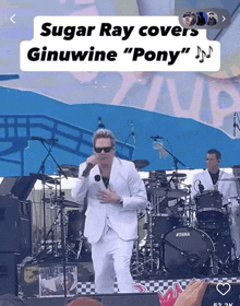 a man in a white suit sings into a microphone while playing drums