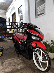a red and black honda motorcycle is parked in front of a white building