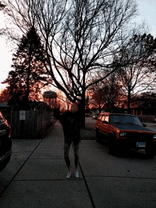 a person standing on a sidewalk in front of a no parking sign and a jeep