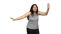 a woman in a gray tank top is dancing with her arm outstretched
