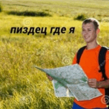 a man is standing in a field holding a map and smiling .