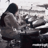 a woman is playing drums on a stage in front of a microphone .