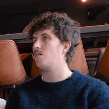 a man in a blue sweater sits in a chair