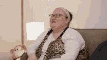 a woman is sitting on a couch with a stuffed monkey behind her and says all cheering