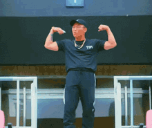 a man wearing a black shirt with the word tipi on it flexes his muscles