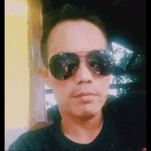 a man wearing sunglasses and a black shirt looks at the camera .