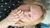 a woman covering her mouth with her hand while wearing a blue ring
