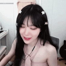 a woman with long black hair and flowers in her hair is sitting in front of a keyboard .