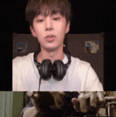 a young man wearing headphones looks at the camera with his hands outstretched