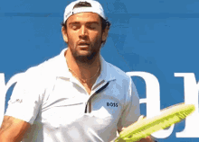 a man wearing a white shirt that says boss on it is holding a tennis racquet