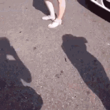 a person is standing on the side of a road with their shadows on the ground .