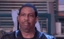 a close up of a man wearing a leather jacket making a funny face .