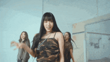 a woman in a camouflage top is dancing with other women