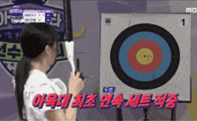 a woman is holding a bow and arrow in front of a target that says 1
