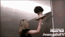 a woman is holding a mannequin head with averagetv written on the bottom right