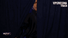 a man in a black shirt is standing in front of a blue curtain with the word amore written on it