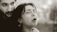 a black and white photo of a man and a woman . the woman is crying and the man is holding her .