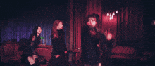 a woman in a black dress is standing in a room with candles