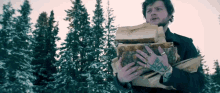 a man with a tattoo on his arm is holding a large pile of logs