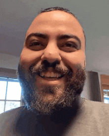 a man with a beard and mustache is smiling for the camera
