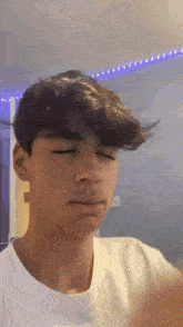 a young man with his eyes closed is making a funny face .