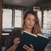 a woman is reading a book in a room with striped walls
