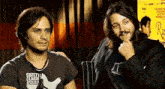 two men are sitting next to each other in a room .