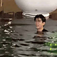 a man is swimming in a pool with a white balloon behind him .