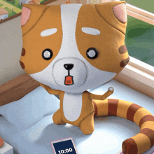 a stuffed animal sitting on a bed next to a cell phone that says 10:00