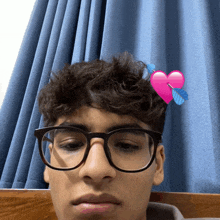 a young man wearing glasses has a pink heart on his forehead