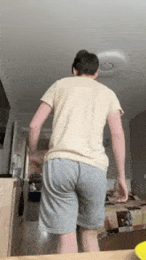 a man in shorts and a yellow shirt is standing in front of a bed