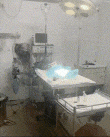 an operating room with a monitor on the wall above a bed
