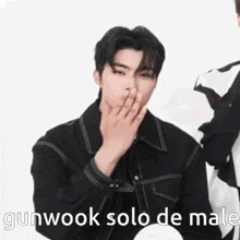 a man in a black jacket is covering his mouth with his hand and the words gunwook solo de male are written below him .